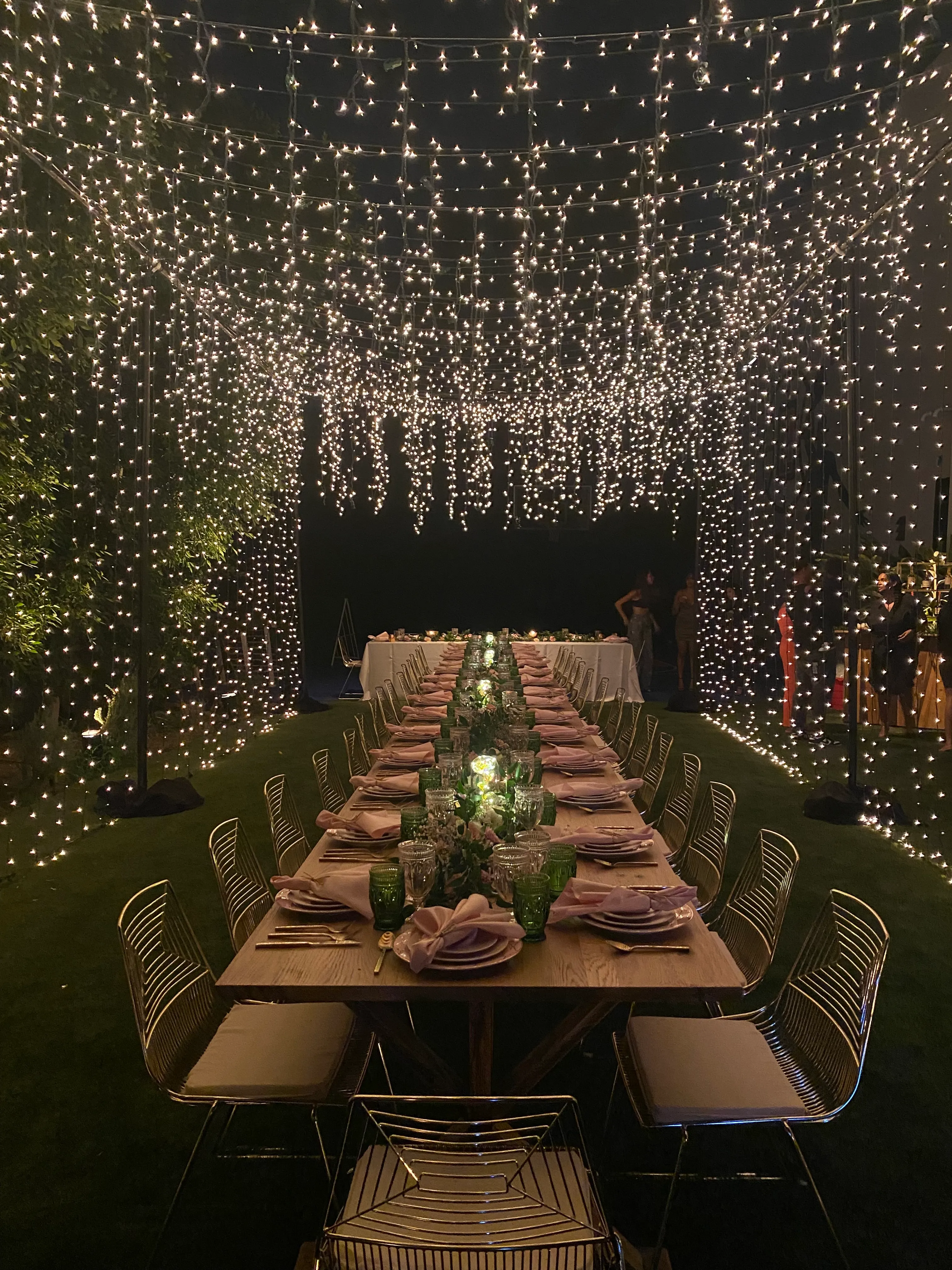 Long dinner table beneath a dense starry canopy of twinkle lights